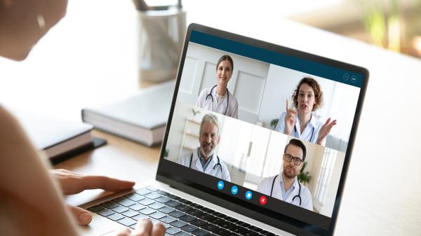 Woman looks at laptop with four medical professionals on a zoom call