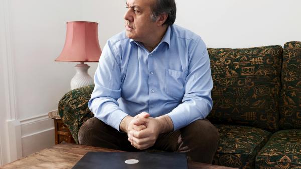 Man sits on couch looking pensively to the side in front of his closed laptop