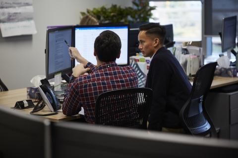 Two staff members look at a computer screen