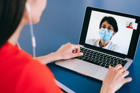 Woman talks to man in mask on laptop